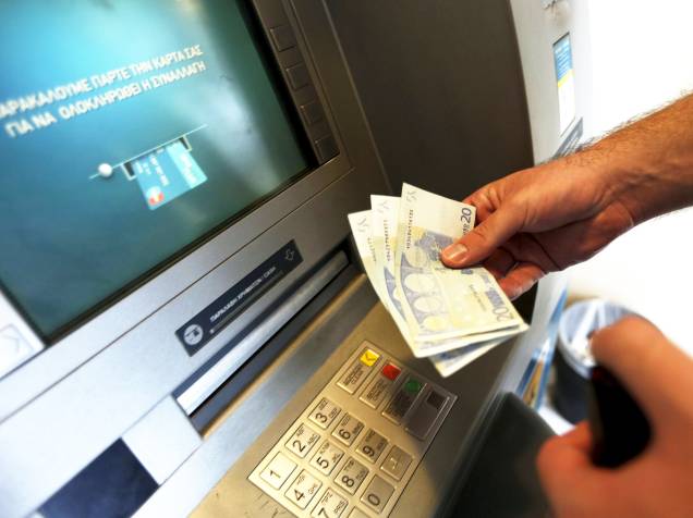Homem saca 60 euros, o limite máximo diário para saque em um caixa eletrônico em Piraeus, próximo a Atenas, na Grécia. Nesta terça-feira (30) termina o prazo para que o país pague uma parcela de 1,6 bilhão de euros ao FMI - 30/06/2015