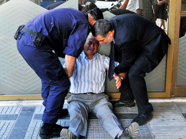 Aposentado grego chora na fila em agência bancária em Atenas nesta sexta-feira (3) após governo permitir que eles façam saques acima de limite imposto