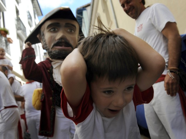 Menino se protege de homem fantasiado durante a "Parada dos gigantes e cabeçudos" no Festival de São Firmino, em Pamplona, Espanha - 08/07/2015