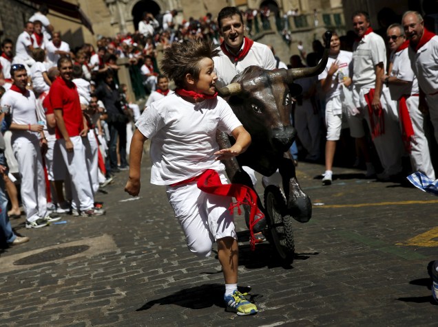 Garoto é perseguido por um touro de brinquedo durante o "Encierro Txixi", a "pequena corrida dos touros", no Festival de São Firmino, em Pamplona - 09/07/2015