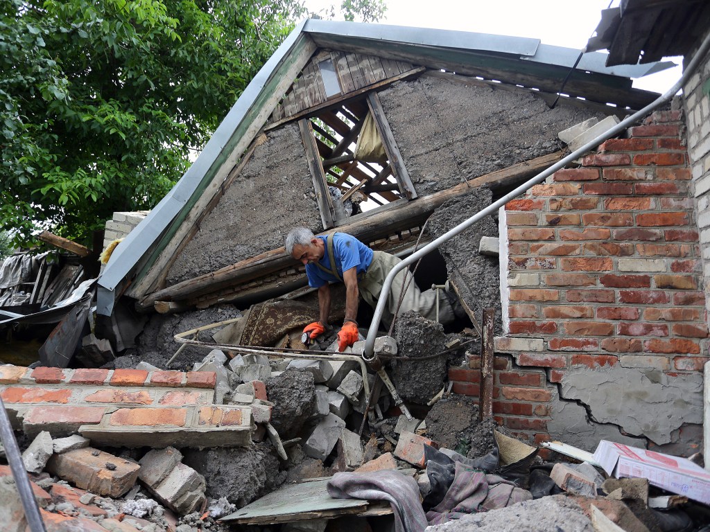 Homem trabalha no resgate do corpo de uma mulher presa debaixo dos escombros de sua casa na vila de Golmovsky, na região de Donetsk, após confronto entre forças ucranianas e separatistas pró-russos - 28/07/2015