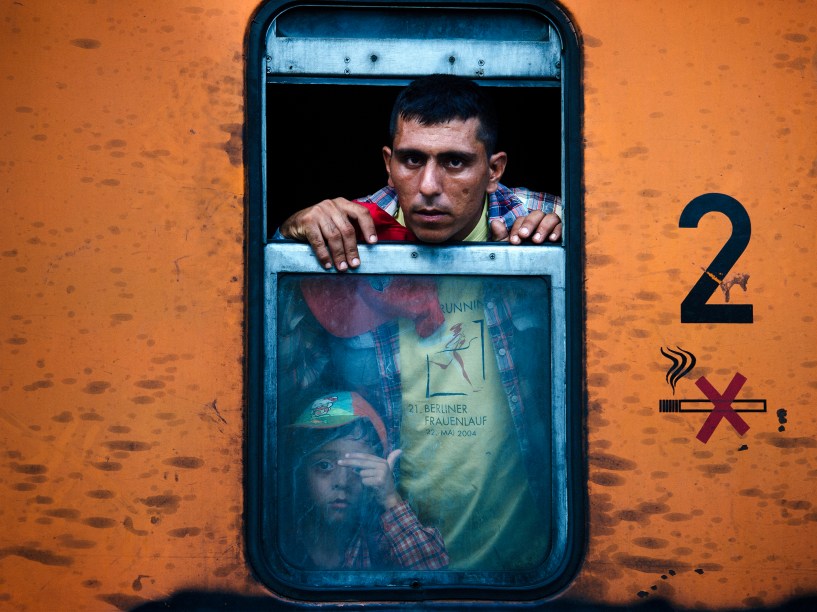Imigrante olha da janela de um trem, com seu filho ao lado, enquanto segue em direção à Sérvia na cidade de Gevgelija, Macedônia - 03/08/2015