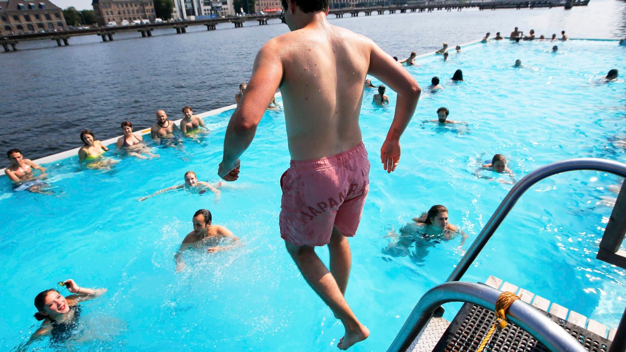 Homem salta em uma piscina flutuante ancorada nas margens do rio Spree, em Berlim, Alemanha - 04/08/2015