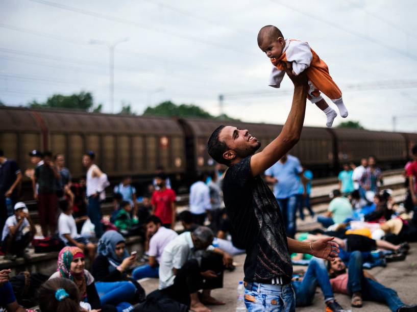 Imigrante levanta seu bebê enquanto espera um trem em direção à fronteira com a Sérvia na estação de Gevgelija, na Macedônia - 06/08/2015