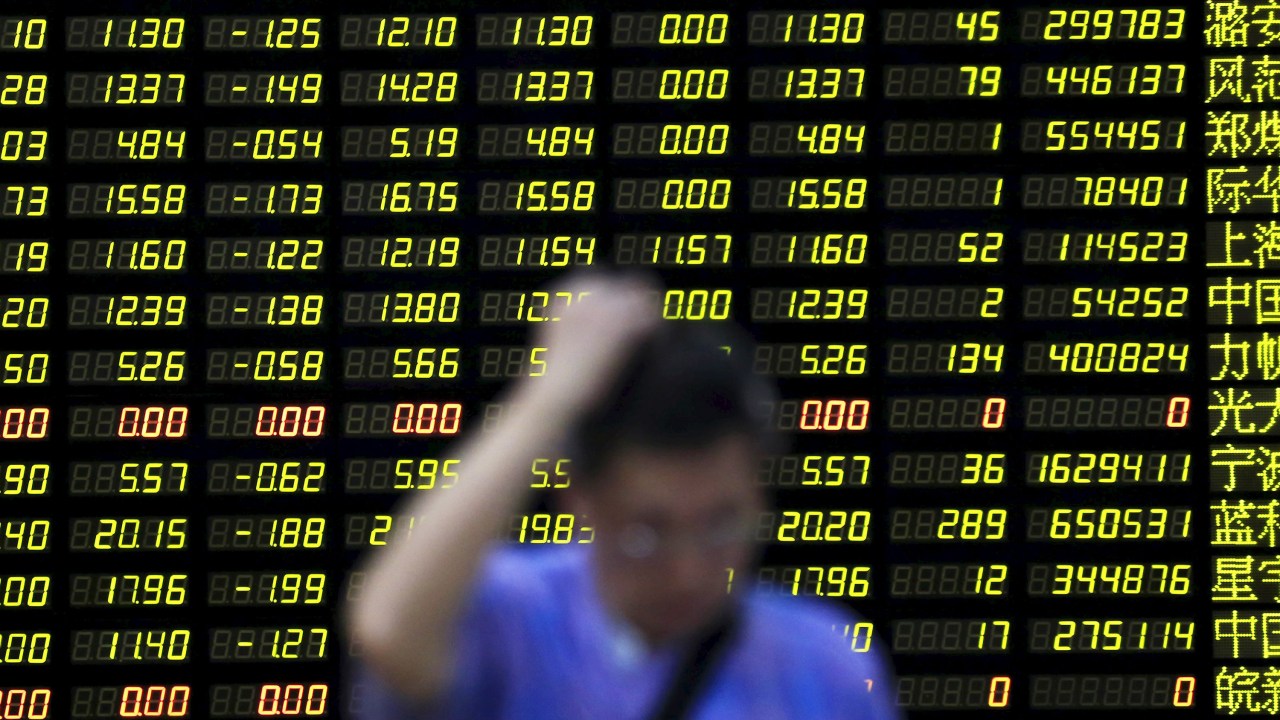 Investidor passa por um painel eletrônico com informações de ações em uma corretora de Xangai, na China. As ações chinesas cairam 8,54% nesta segunda-feira (24)