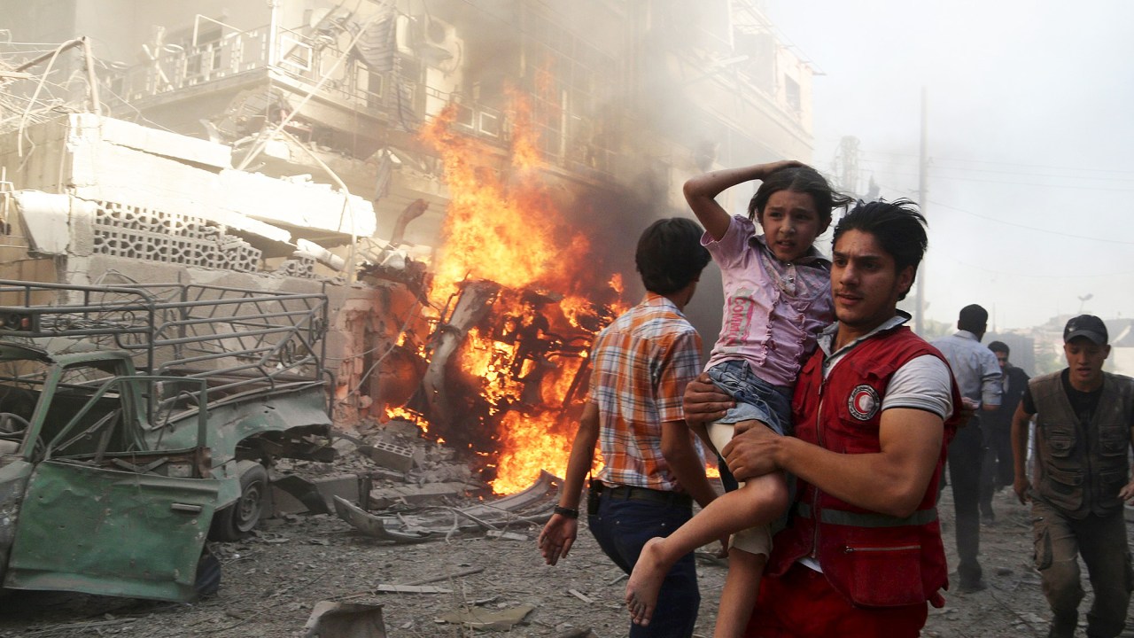 Bombeiro carrega uma criança após uma explosão, o que ativistas disseram ter sido um bombardeio de forças leais ao governo de Bashar al-Assad no bairro de Douma, em Damasco, capital da Síria