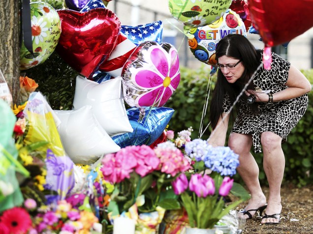 Mulher deixa flores em um memorial em frente à sede da WDBJ7 em Roanoke, Virgínia, nos EUA. Uma repórter e um cinegrafista da emissora foram mortos durante uma transmissão ao vivo após serem baleados por Vester Flanagan, um ex-funcionário da TV