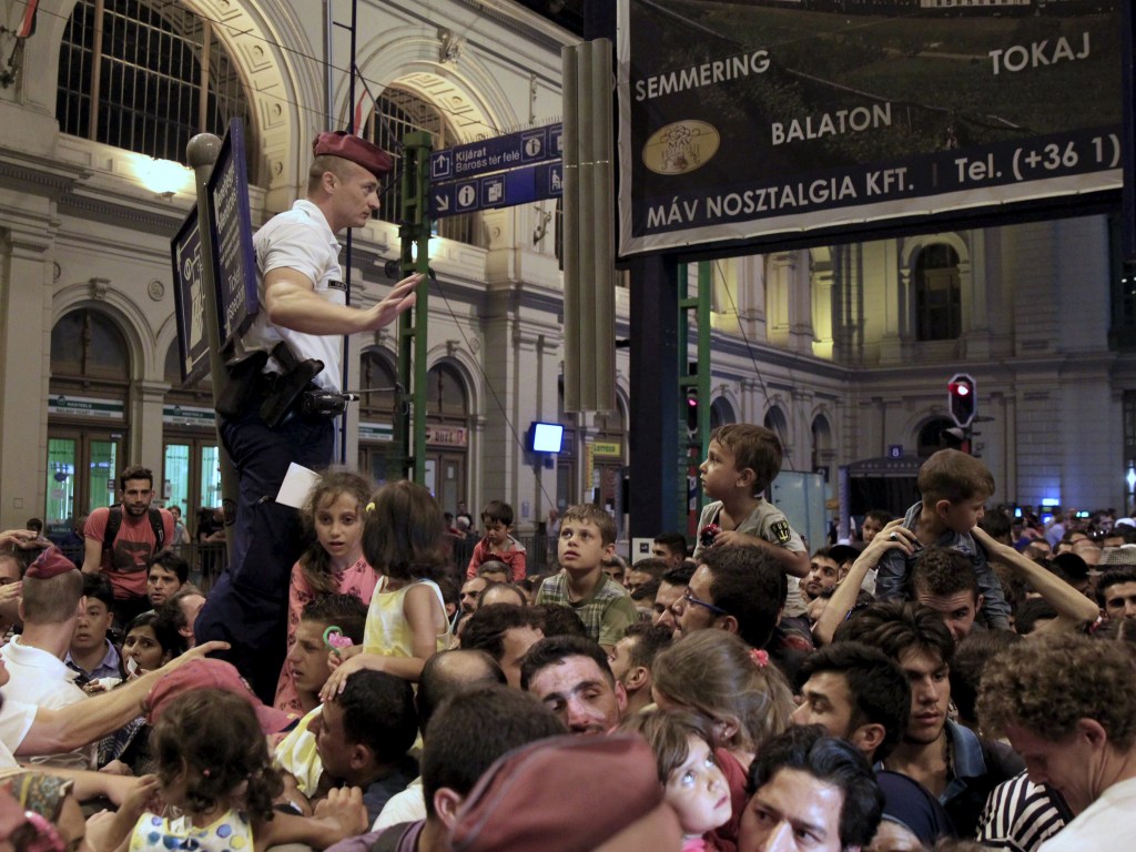 Policial tenta controlar imigrantes após novas regras serem anunciadas obrigando cada passageiro a ter um assento em trens que saem de Budapeste para o oeste, na Hungria - 31/08/2015