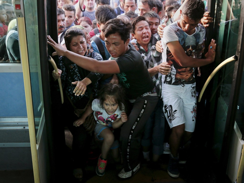 Refugiados e imigrantes se empurram para entrar em um ônibus após desembarcarem de um navio no porto de Pireu, na Grécia - 07/09/2015