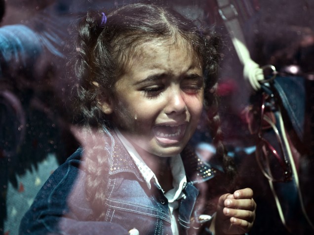 Criança refugiada chora dentro de um ônibus lotado transportando imigrantes e refugiados às estações de metrô e trem, após desembarcar de uma balsa do governo no porto de Pireus, em Atenas, Grécia - 08/09/2015
