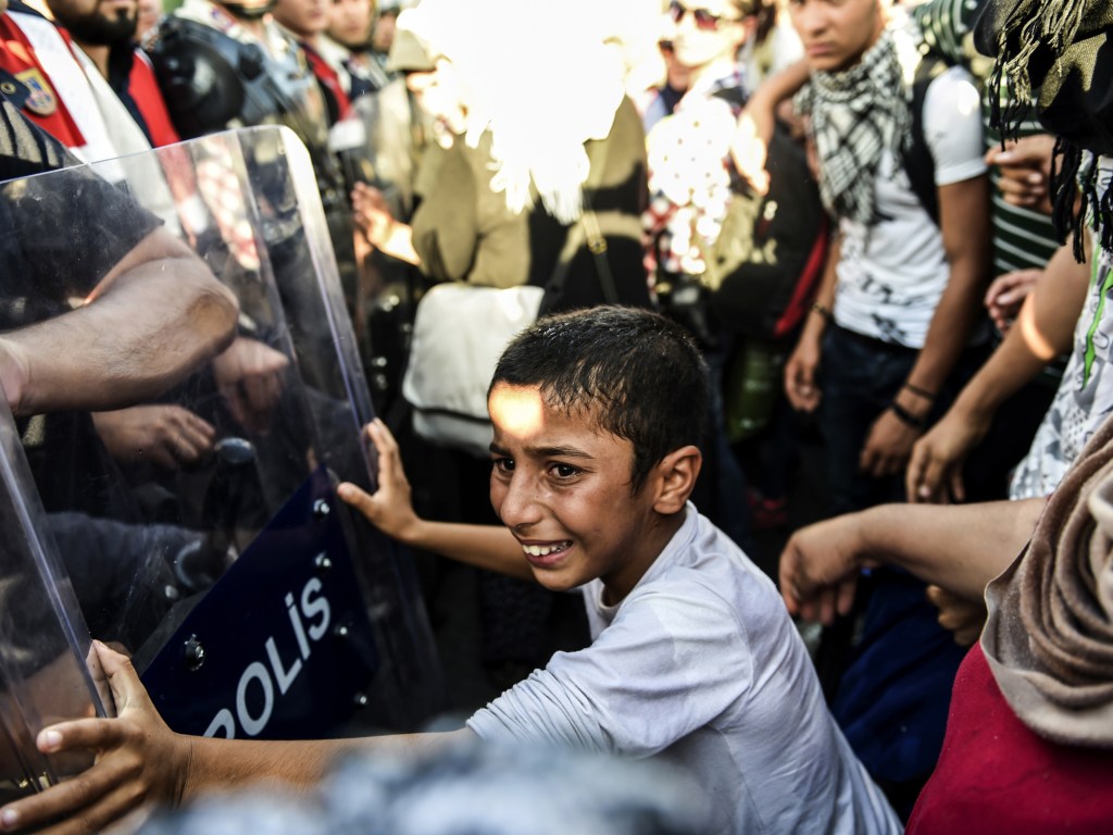 Garoto sírio empurra uma barricada policial enquanto refugiados marcham ao longo de uma estrada em direção à fronteira com a Grécia, na cidade turca de Edirne - 18/09/2015