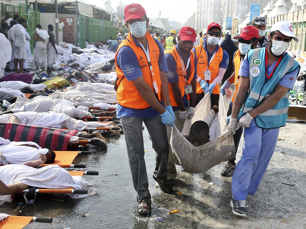 Voluntários carregam corpos do acidente em Meca. Uma confusão durante peregrinação matou centenas na Arábia Saudita
