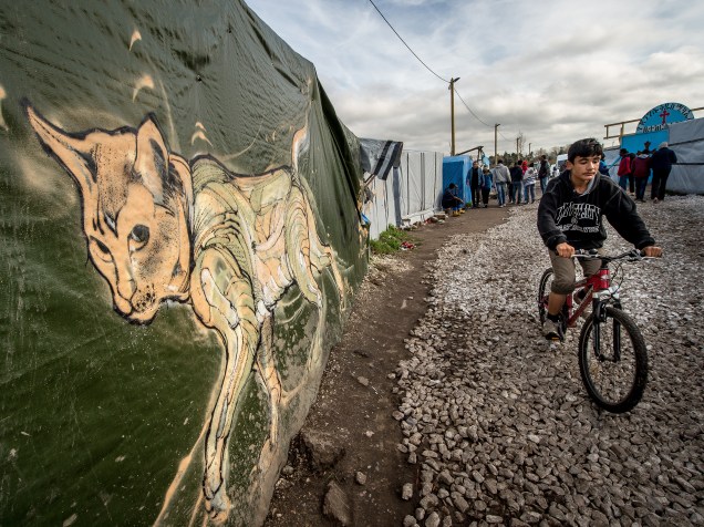 Jovem anda de bicicleta através do acampamento improvisado que abriga milhares de refugiados e é conhecido como Selva na cidade francesa de Calais -  29/10/2015