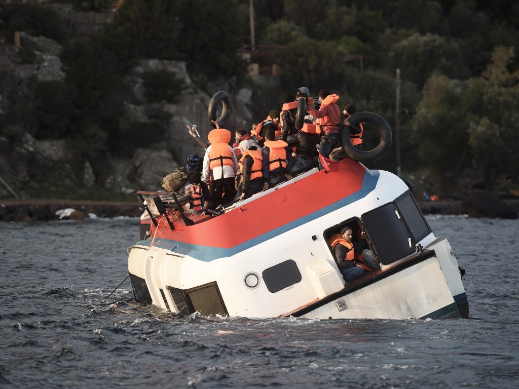 Refugiados e imigrantes pedem ajuda enquanto o barco que estão afunda na costa da ilha de Lesbos, após atravessar o Mar Egeu vindo da Turquia - 30/10/2015