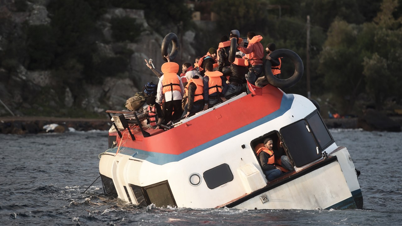 Refugiados e imigrantes pedem ajuda enquanto o barco que estão afunda na costa da ilha de Lesbos, após atravessar o Mar Egeu vindo da Turquia - 30/10/2015