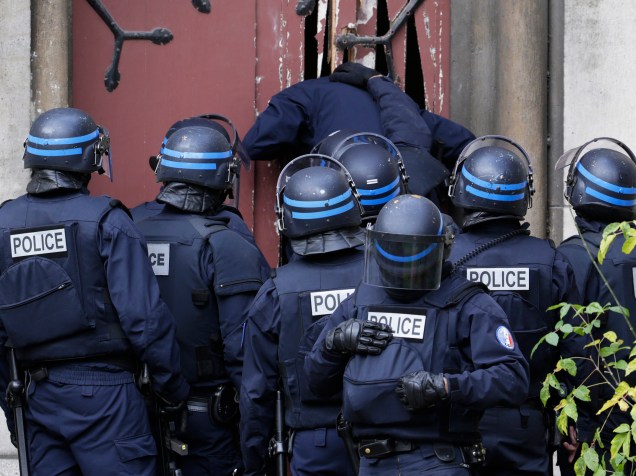 Policiais arrebentam porta de uma igreja em Sant-Denis, subúrbio de Paris, para manter a área segura durante caçada de suspeitos de ligação com os ataques terroristas - 18/11/2015