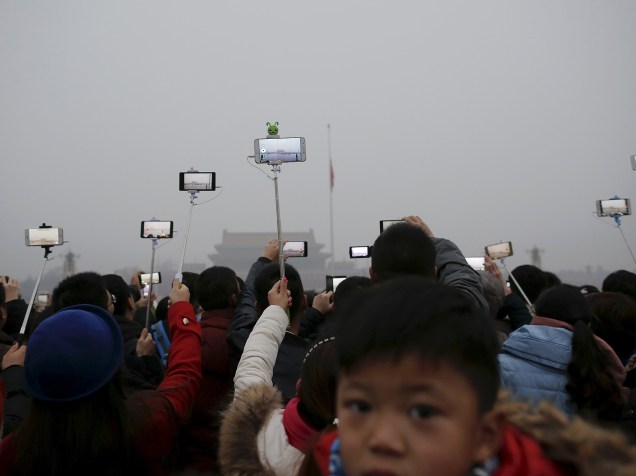 <p>Chineses durante uma cerimônia de hasteamento da bandeira em meio a fumaça pesada na Praça Tiananmen, nesta quarta-feira (09). Pequim está em "alerta vermelho" para a poluição do ar</p>
