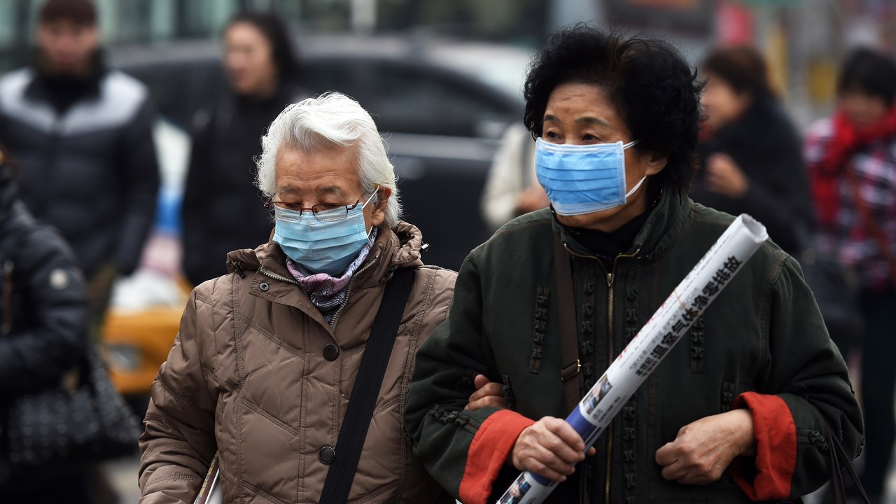 Mulheres usam máscara para se proteger da poluição em Pequim, nesta segunda-feira (14)