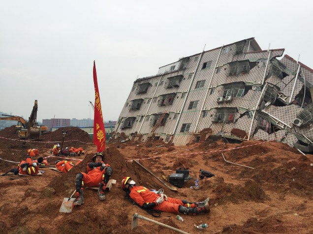 Equipe de resgate descansa próximo ao local onde havia um parque industrial da cidade de Shenzhen, no sul da China. Um deslizamento de terra neste domingo (20) deixou mais de 90 desaparecidos
