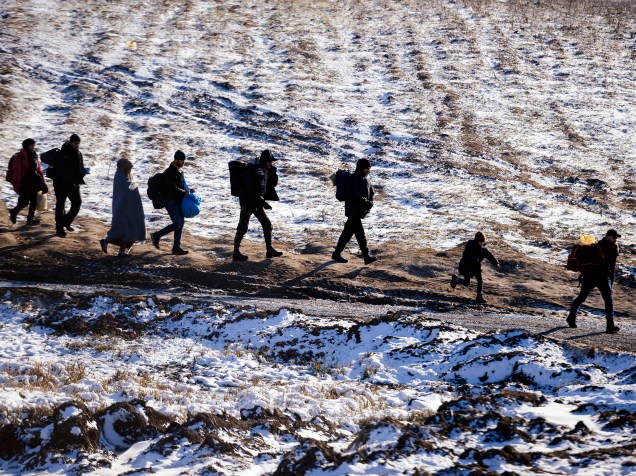 Refugiados caminham através de campos cobertos de neve através da fronteira entre a Macedônia e a Sérvia, próximo ao vilarejo de Miratovac, na Sérvia - 19/01/2016