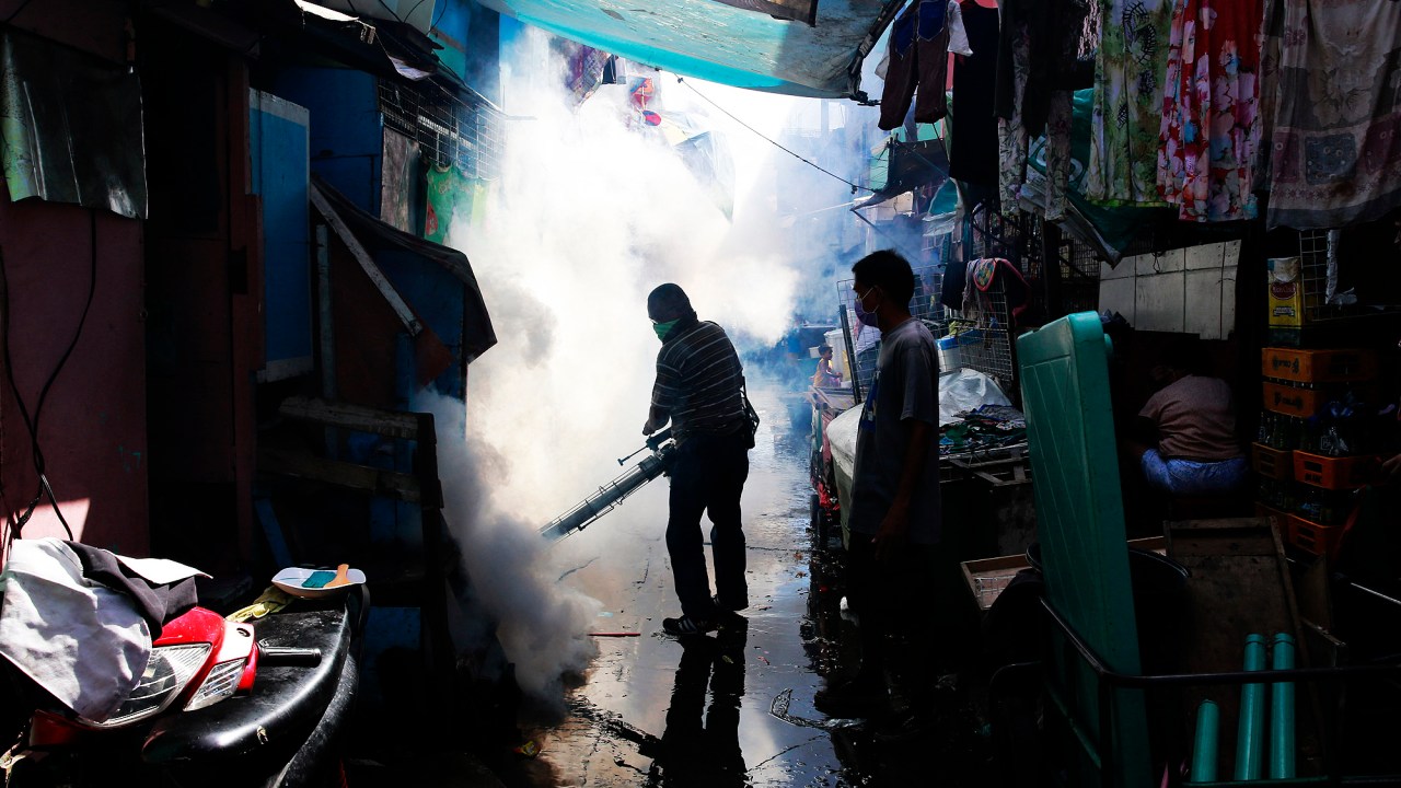 Um agente municipal aplica fumigante em bairro de Paranaque, na região metropolitana de Manila, nas Filipinas, para prevenir a proliferação dos mosquitos Aedes