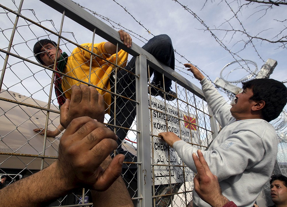 Imigrante em cerca na fronteira da Grécia com a Macedônia, depois da Macedônia fechar suas fronteiras, próximo à aldeia de Idomeni, nesta segunda-feira (22)