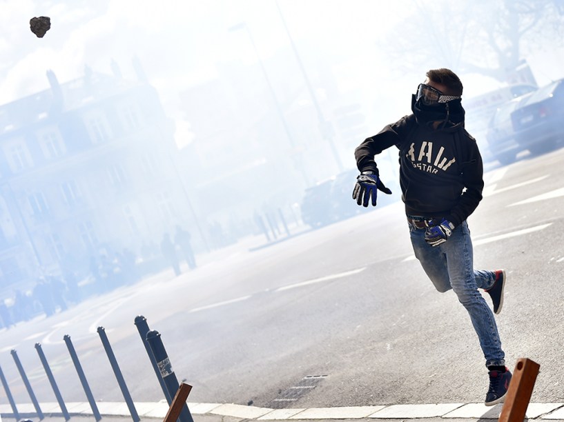 Manifestante atira pedra contra a polícia durante protesto contra as reformas trabalhistas, na França - 31/03/2016