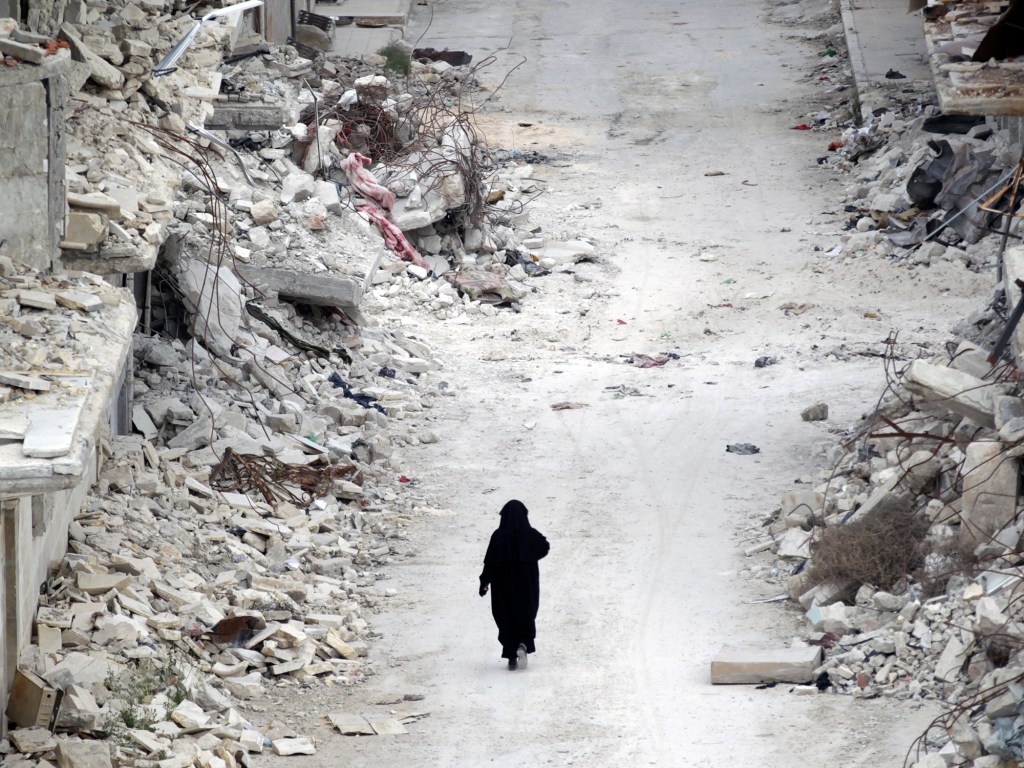 Mulher caminha por entre escombros na província de Idlib, na Síria