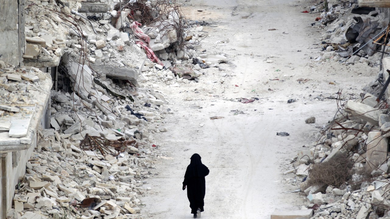 Mulher caminha por entre escombros na província de Idlib, na Síria
