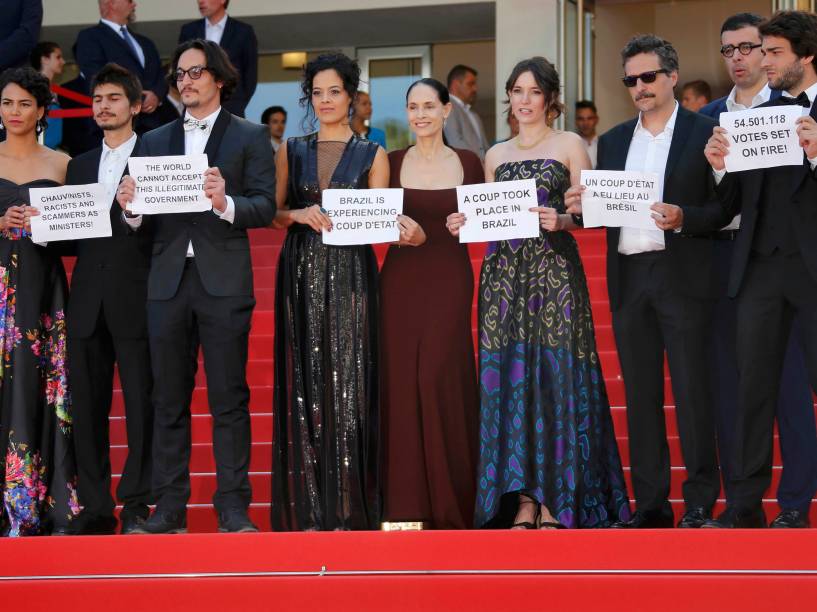 O diretor Kleber Mendonça Filho e o elenco do filme brasileiro Aquarius seguram cartazes em protesto contra o impeachment da presidente Dilma Rousseff no tapete vermelho do 69º Festival de Cinema de Cannes, na França - 17/05/2016