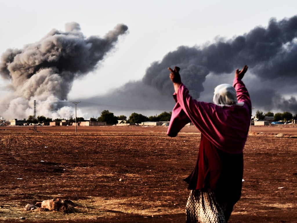 Mulher reage ao ver fumaça na cidade síria de Ain al-Arab, depois de um bombardeio liderado pelos Estados Unidos contra o Estado Islâmico (EI)
