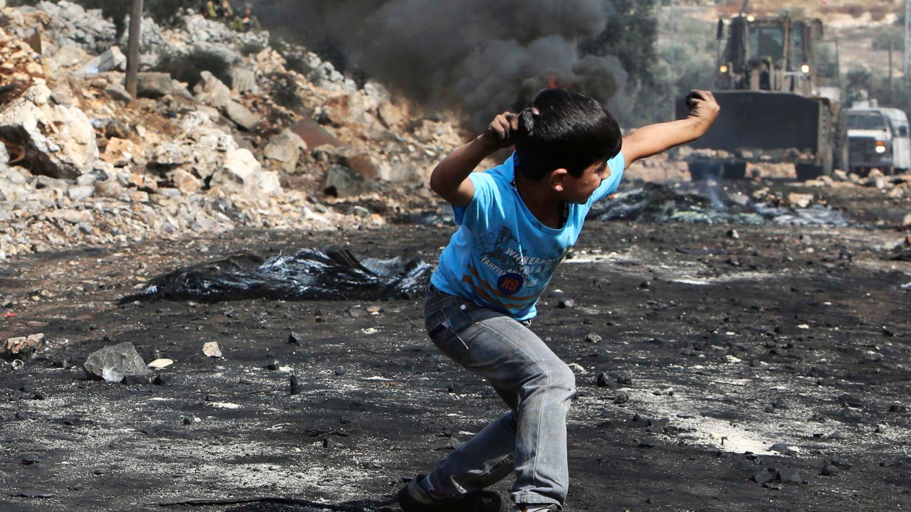 Menino palestino atira pedra nas Forças de Defesa de Israel durante confrontos na Cisjordânia