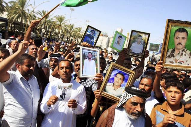 Cidadãos iraquianos protestam nas ruas de Kerbala, sul do Iraque, com fotos de parentes supostamente executados pelo Estado Islâmico