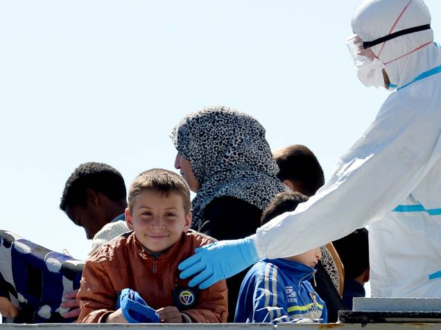 Oficial naval interage com menino que estava entre os imigrantes resgatados do navio com destino à Grécia