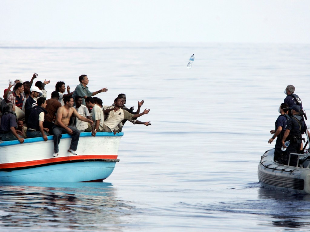 Forças armadas atiram garrafas de água para um grupo de imigrantes ilegais durante operação de resgate na costa da Líbia