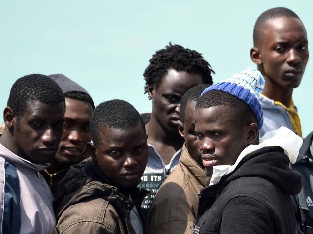 Imigrantes esperam equipe de resgate para desembarcar no porto siciliano em Catânia