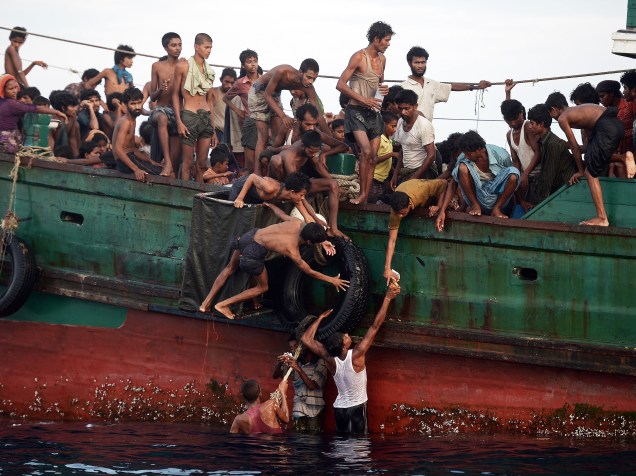 Imigrantes pegam alimentos jogados por helicóptero do exército tailandês, nas águas da ilha do sul de Koh Lipe, no mar de Andaman