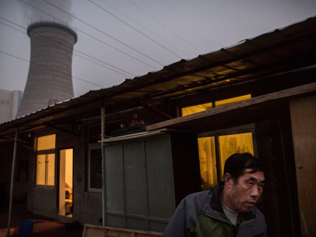 <p>Imigrante chinês caminha para sua casa próximo a uma usina em Pequim, China. Governo chinês estabeleceu 2030 como o prazo para que o país atinja seu pico de emissão de dióxido de carbono, o que cientistas atribuem como a causa principal das mudanças climáticas</p>