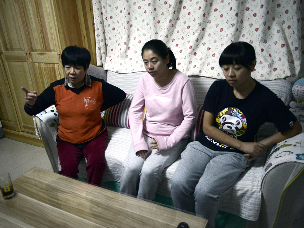 Li Xue sentada com sua irmã Li Bin (direita) e sua mãe Bai Xiuling (esquerda)