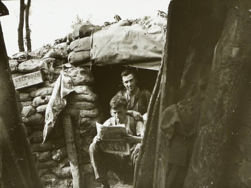 Soldados leem jornal em um acampamento de Ploegsteert, na Bélgica, durante o verão de 1916 <br><br>