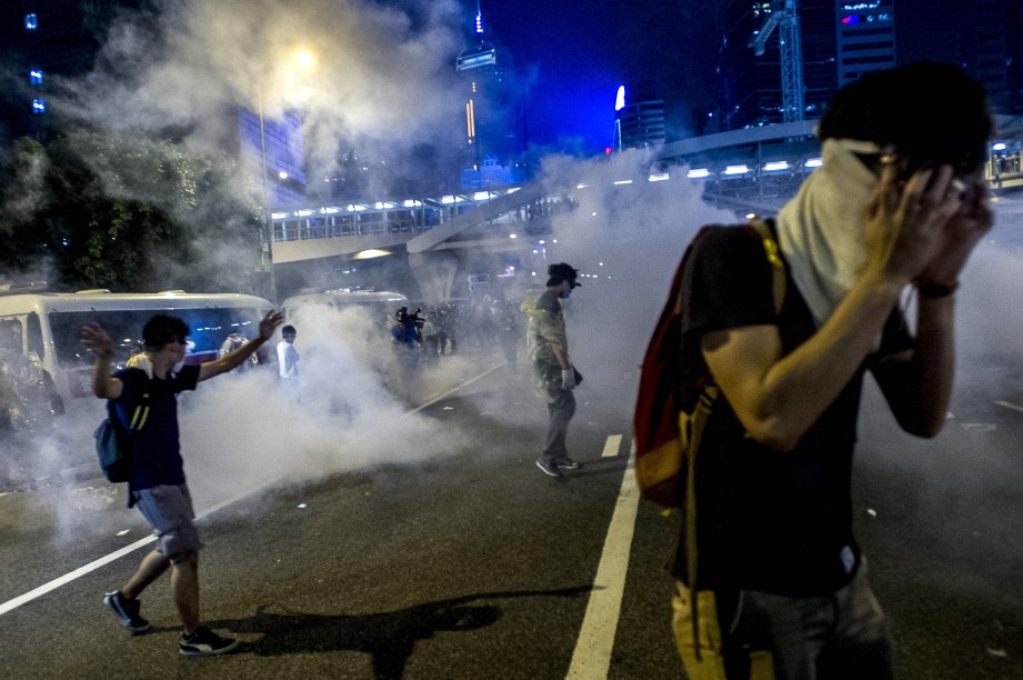 Manifestantes pró-democracia se protegem depois que a polícia usou gás lacrimogêneo para dispersar a multidão próximo a sede do governo de Hong Kong, na China