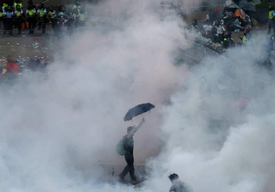 Um manifestante anda em meio à fumaça de gás lacrimogêneo disparado por policiais durante um ato pró-democracia, em frente à sede do governo de Hong Kong, na China