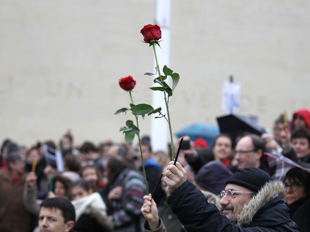 Dezenas de pessoas levam flores e lápis em um protesto na Praça do Memorial, na cidade de Caen, em memória às vítimas mortas no atentado terrorista que atingiu a França na última semana