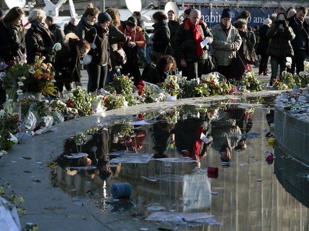 Dezenas de pessoas depositam flores e cartazes próximo a estátua de Marianne, na Praça da República, região leste de Paris, em homenagem às vítimas dos atentados terrorista que assolaram o país na última semana