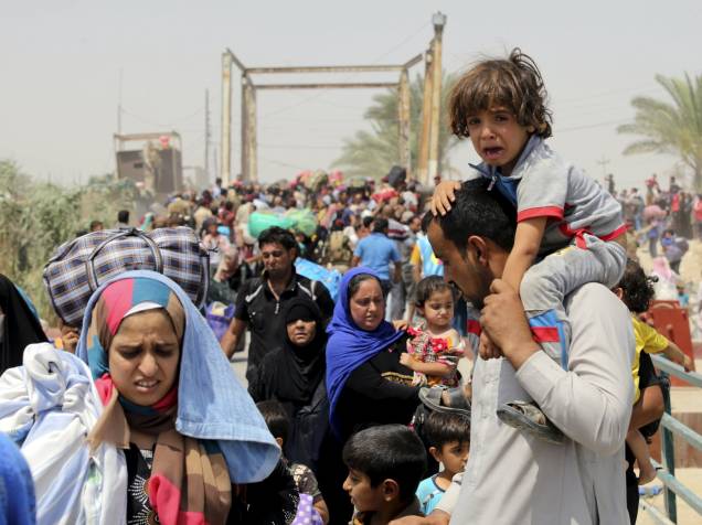 Homem desabrigado fugindo da violência em Ramadi carrega criança nas costas, próximo a Bagdá, Iraque
