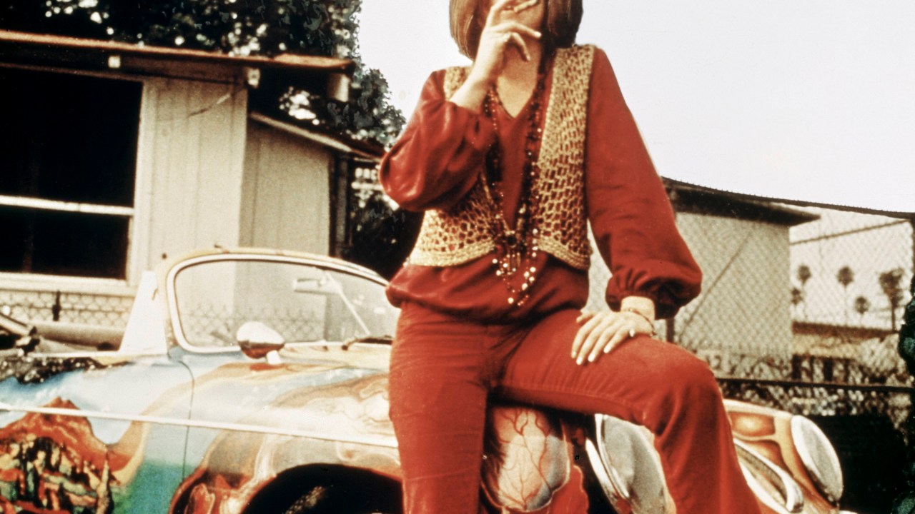 American singer-songwriter Janis Joplin (1943 - 1970) with her 1965 Porsche 356C Cabriolet, circa 1969. The car features a psychedelic paint job by Joplin's roadie, Dave Richards. (Photo by RB/Redferns)