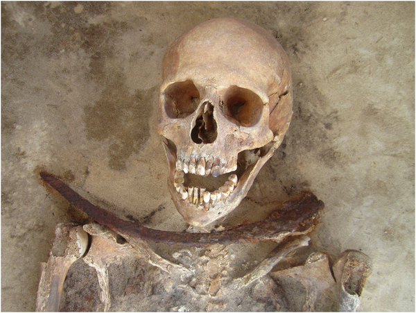 Esqueleto de mulher de 30 a 39 anos com foice colocada no pescoço