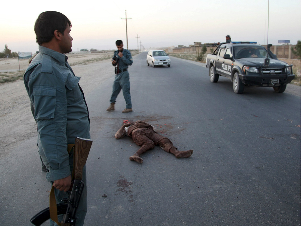 Policiais afegões observam o corpo de um talibã, em Kunduz