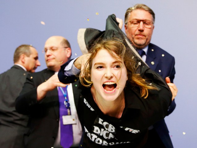 Seguranças detém a manifestante que pulou em cima da mesa do presidente do Banco Central Europeu, Mario Draghi
