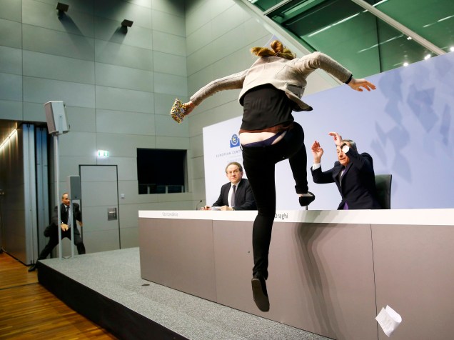 Jovem pula em cima da mesa do presidente do BCE durante coletiva de imprensa